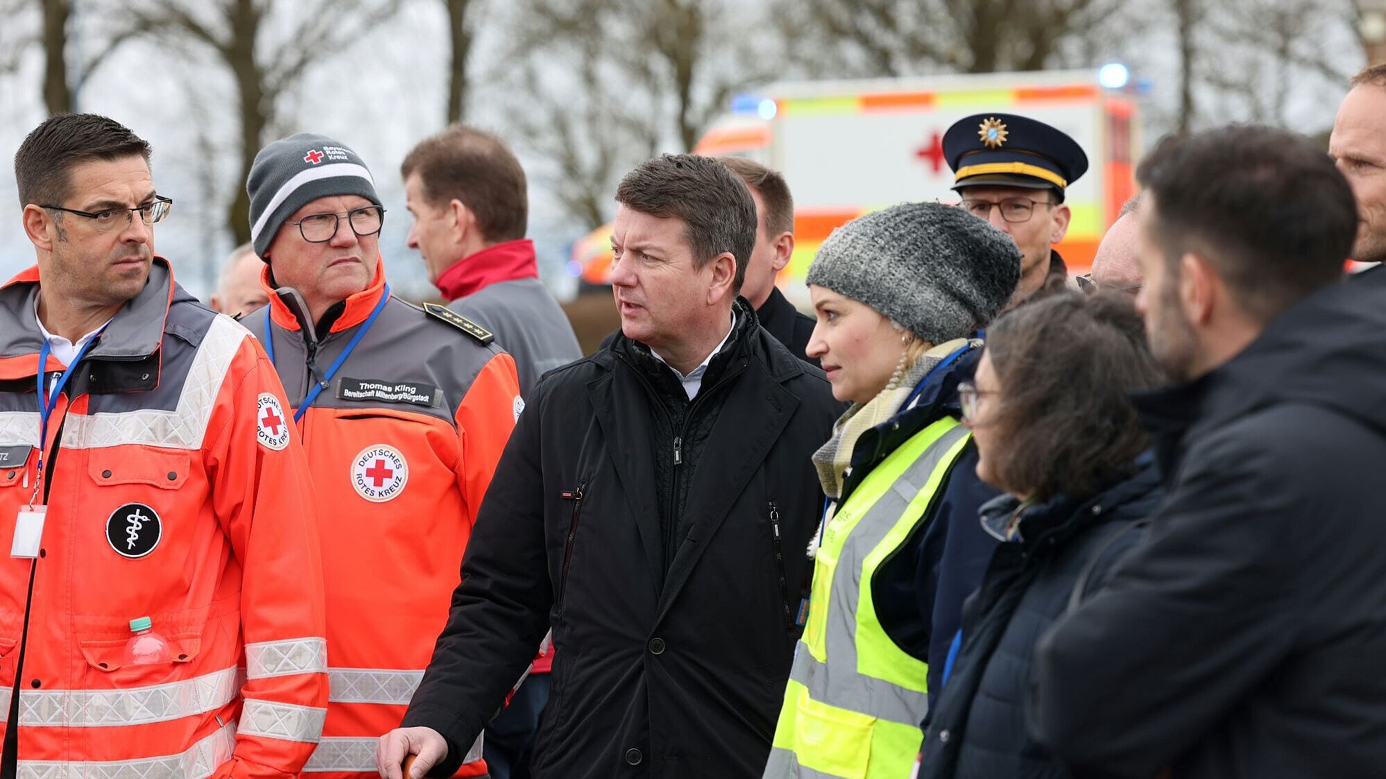 Zwei BRK-Rettungskräfte, Innenstaatssekretär Sandro Kirchner und weitere Vertreterinnen Vertreter der Rettungsdienste und der Polizei im Gespräch. 