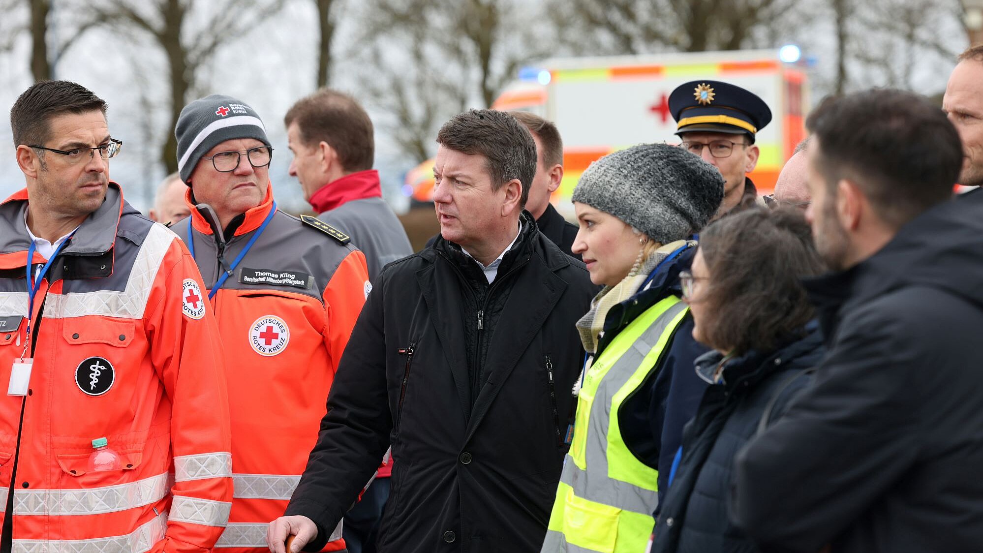 Zwei BRK-Rettungskräfte, Innenstaatssekretär Sandro Kirchner und weitere Vertreterinnen Vertreter der Rettungsdienste und der Polizei im Gespräch. 