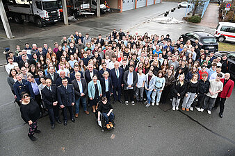 Eine Gruppe von Menschen versammelt sich vor einem Gebäude für ein gemeinsames Foto.