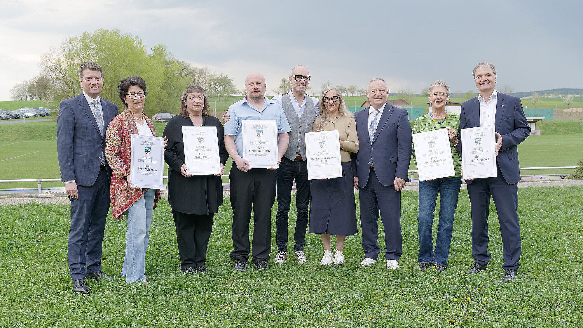 Gruppenbild bei der Überreichung der Sportehrenbriefe, alle stehen auf einer grünen Wiese.