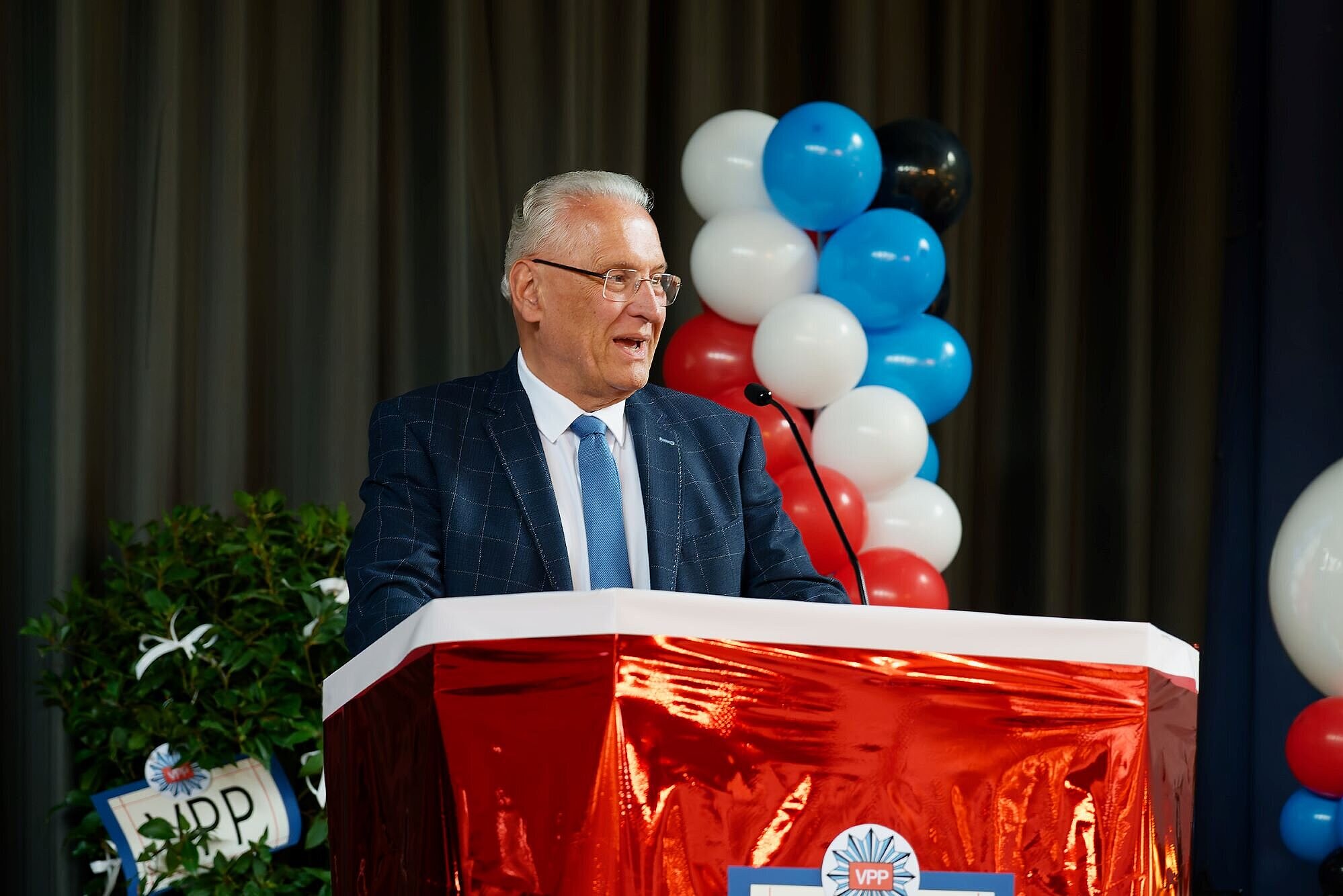 Innenminister Joachim Herrmann am Rednerpult, hinter im bunte Luftballons anlässlich der Feierlichkeiten zum 75. Geburtstag der VPP