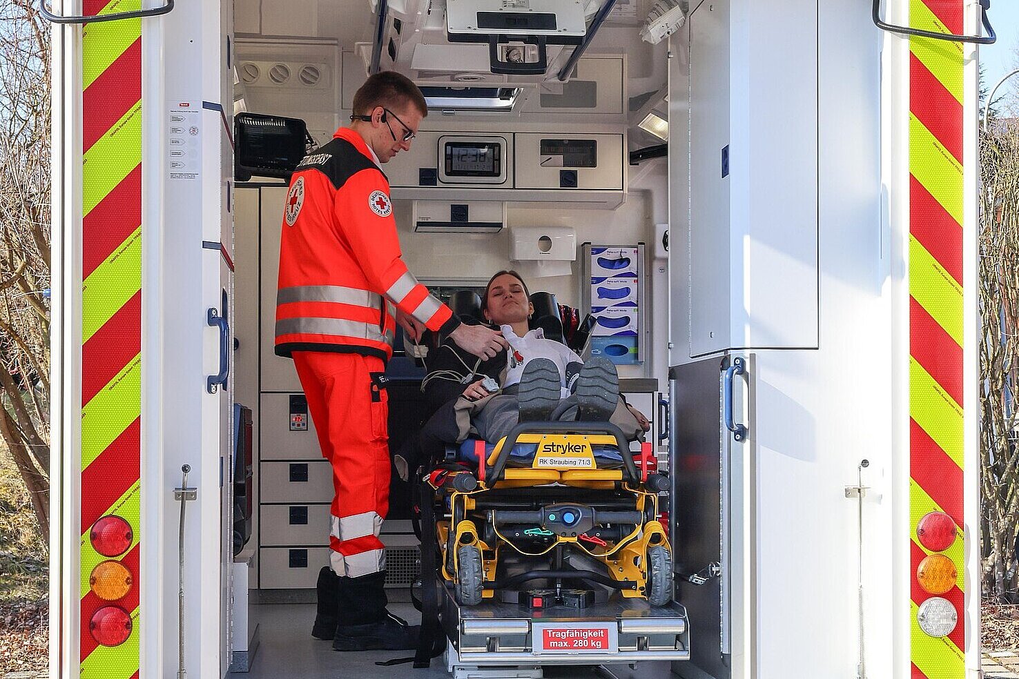 Eine Person wird im Innenraum eines Krankenwagens von einem Notarzt untersucht
