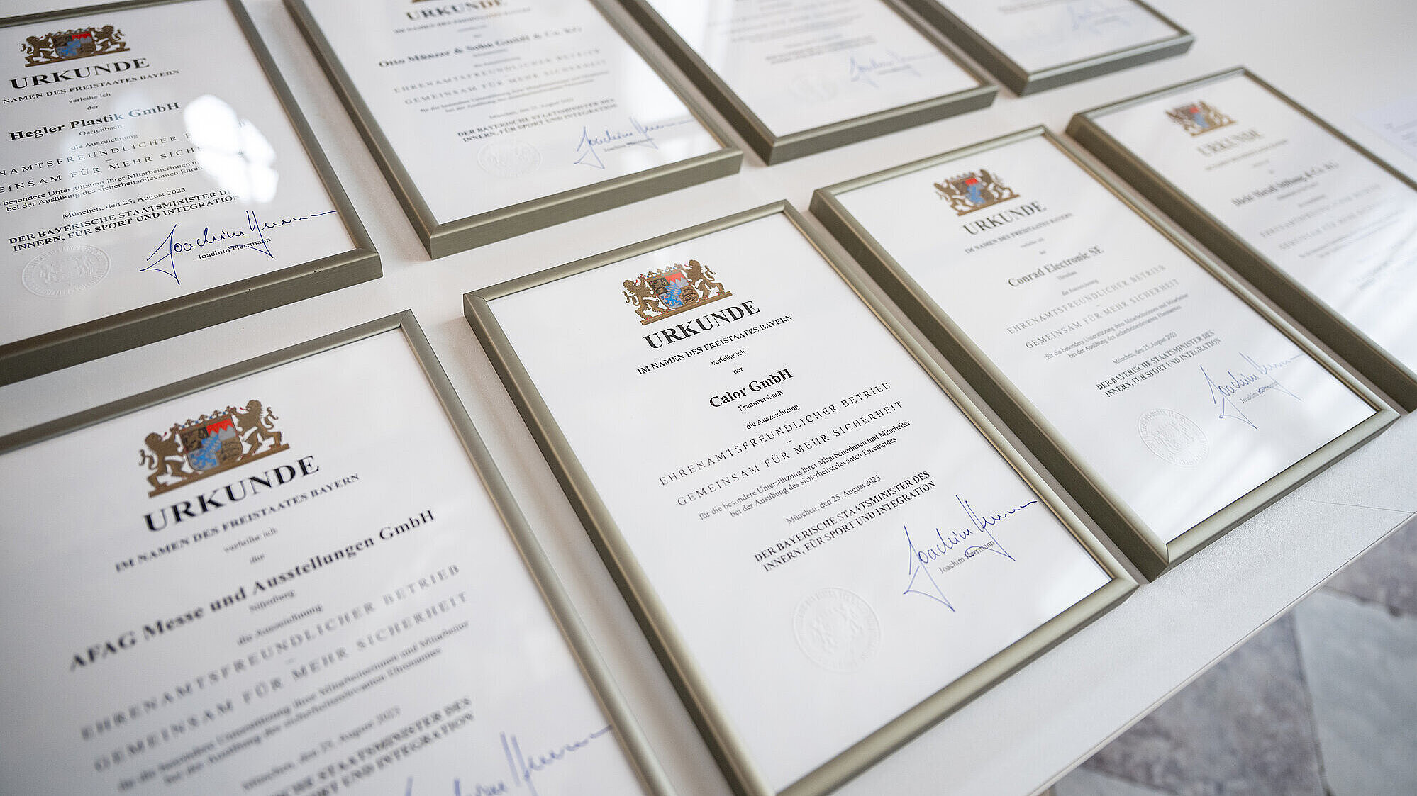 Mehrere Urkunden des StMI für ehrenamtsfreundliche Betriebe im Rahmen auf einem Tisch liegend