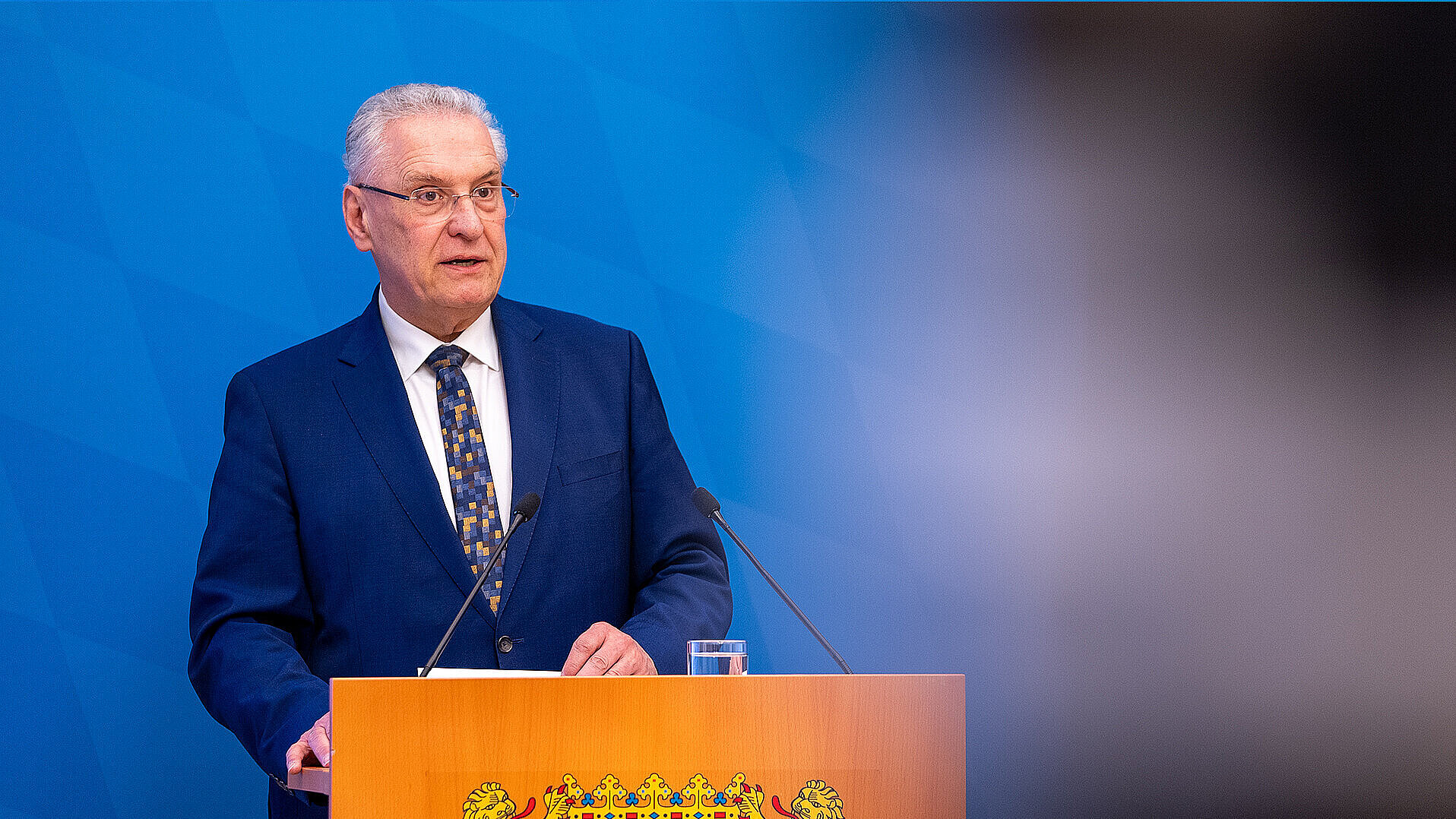 Innenminister Joachim Herrmann ernst blickend am Rednerpult