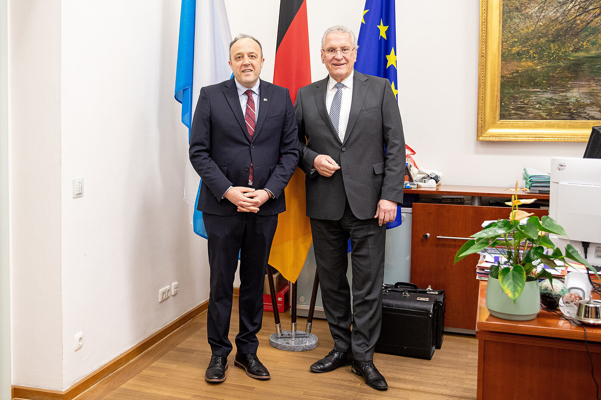 im Bild: Innenminister Joachim Herrmann und der ukrainischen Generalkonsul Yurii Nykytiuk vor einem Fahnenset im Ministerbüro