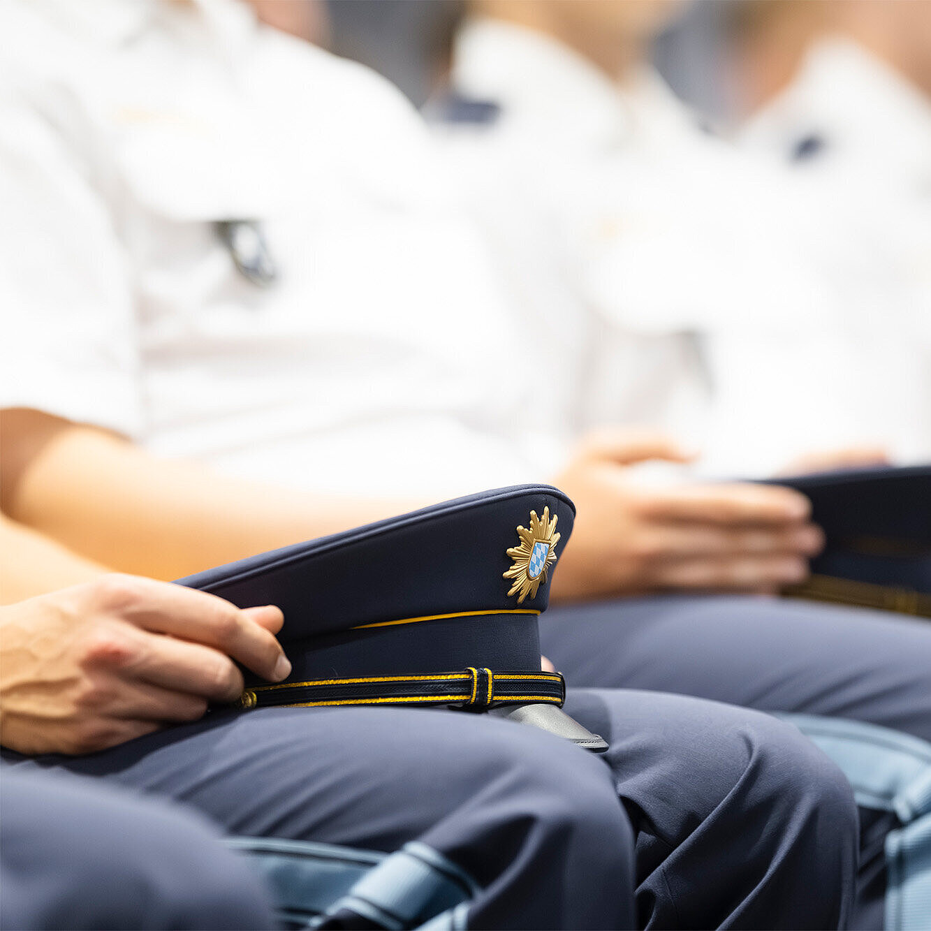 Detailaufnahme von Polizisten sitzend in der Reihe mit Hüten auf dem Schoß