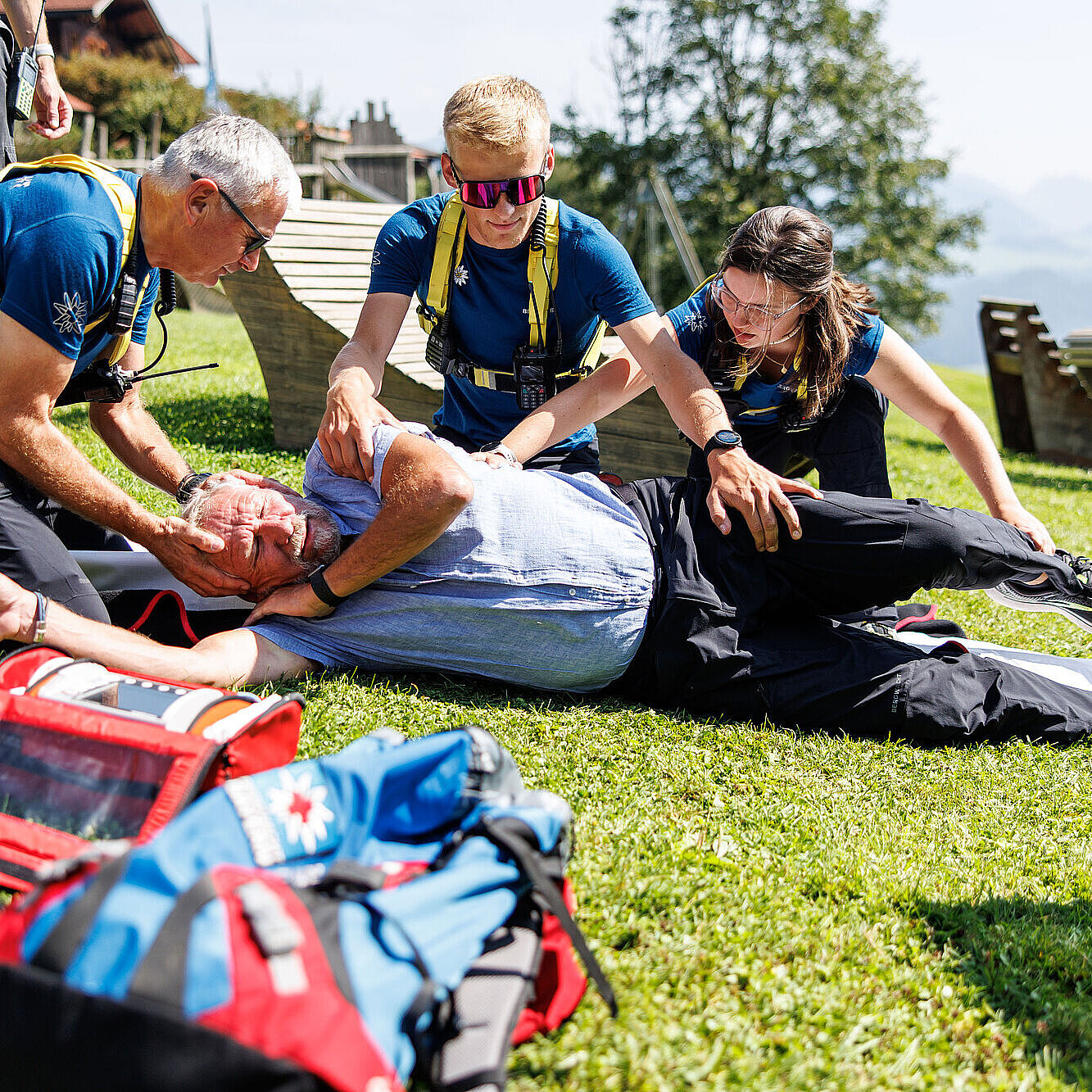 Sanitäter der Bergwacht bringen Verletzte Person auf einer Wiese in stabile Seitenlage