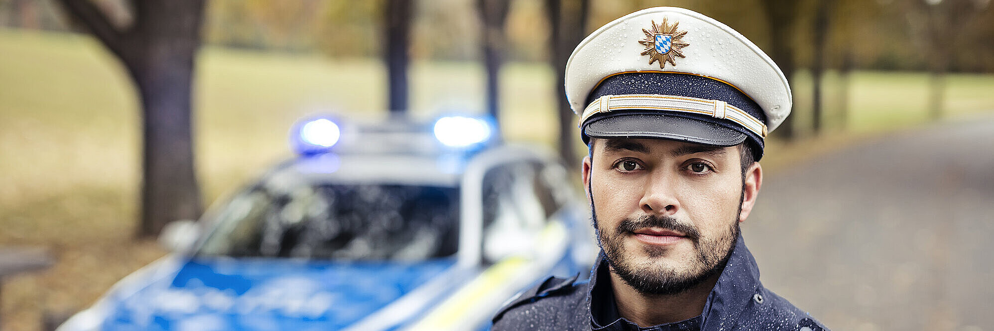 Polizist in Uniform vor Streifenwagen