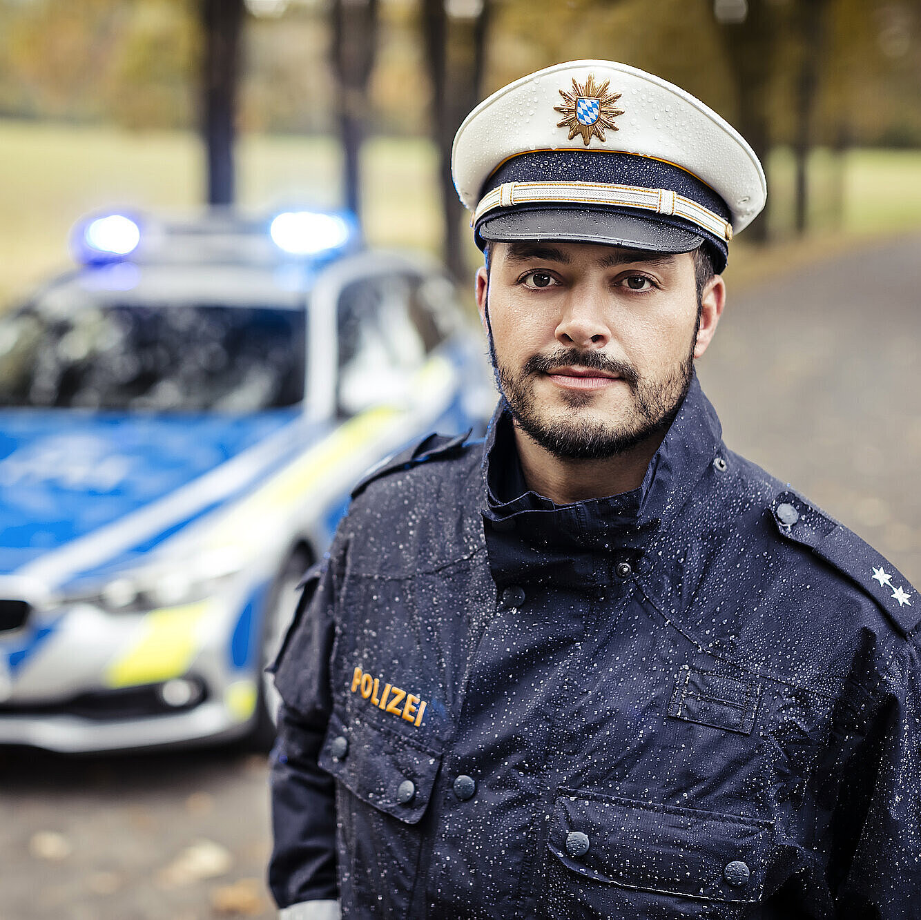 Polizist in Uniform vor Streifenwagen
