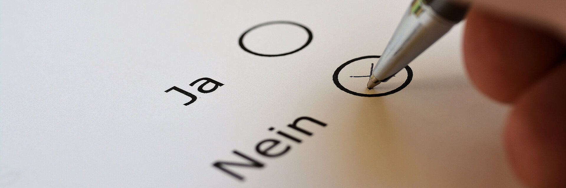Nahaufnahme von Hand die ein Papier mit Ja/Nein ankreuzt
