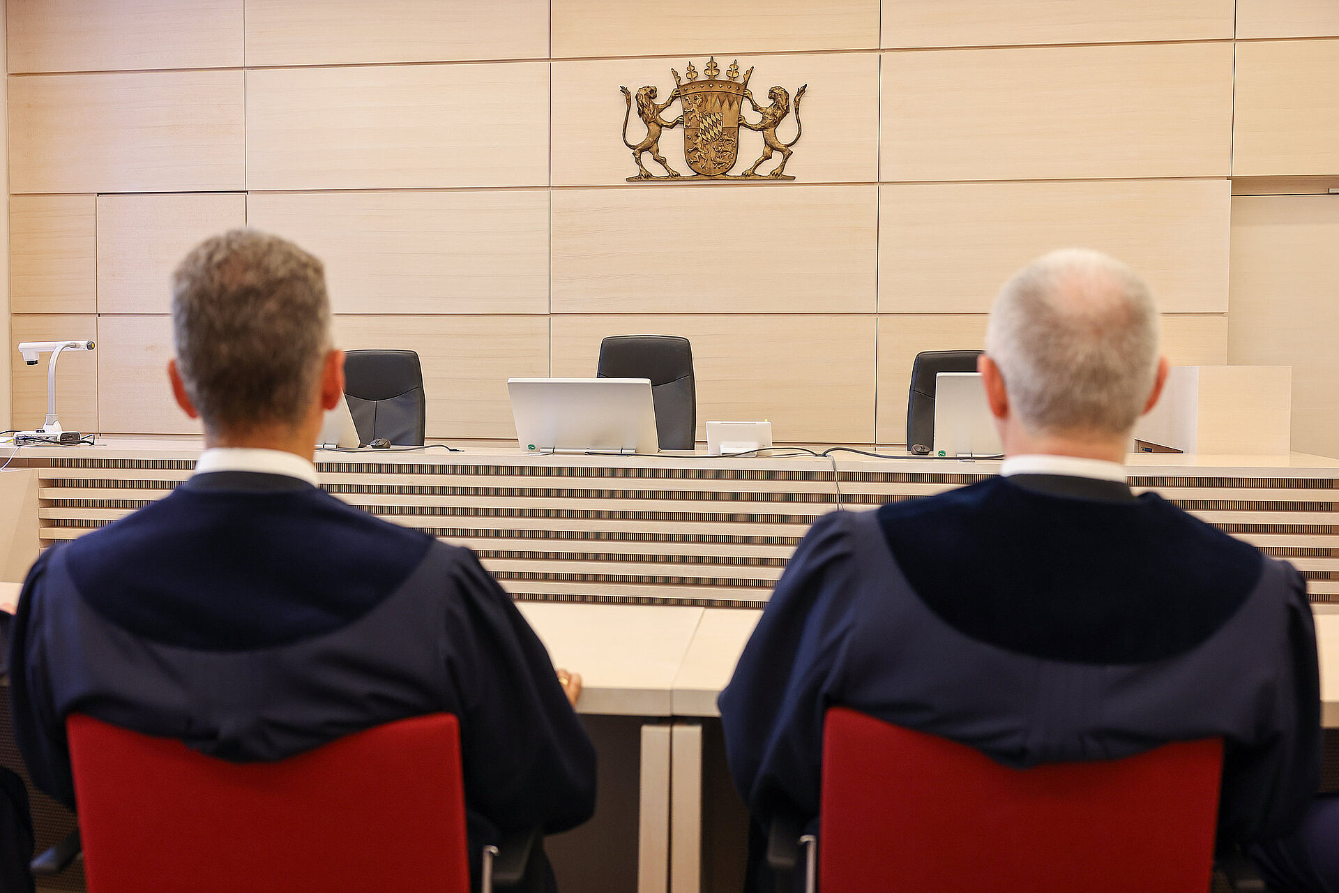 Zwei Richter in ihrer Robe sitzend von hinten im Sitzungssaal des Gerichts