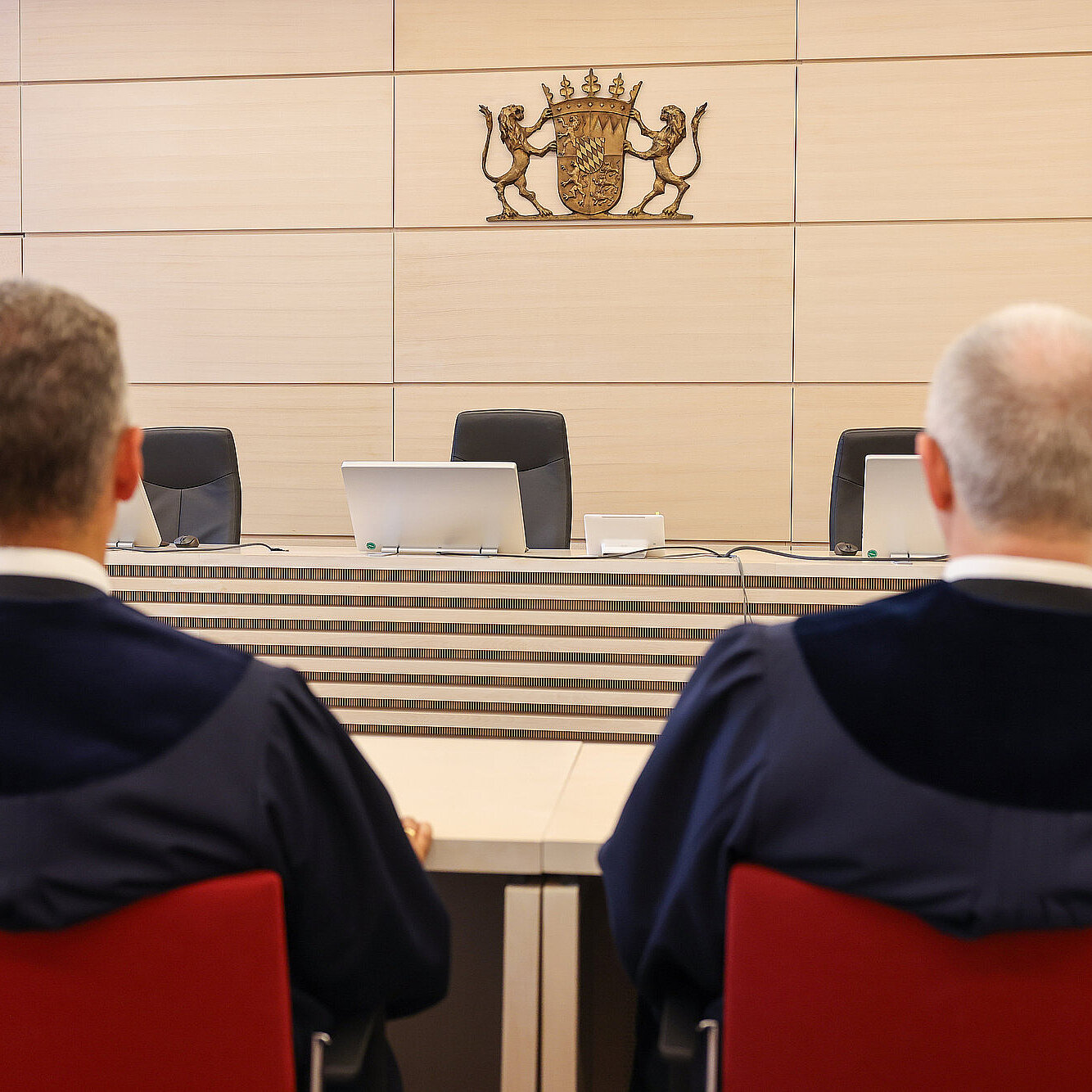 Zwei Richter in ihrer Robe sitzend von hinten im Sitzungssaal des Gerichts