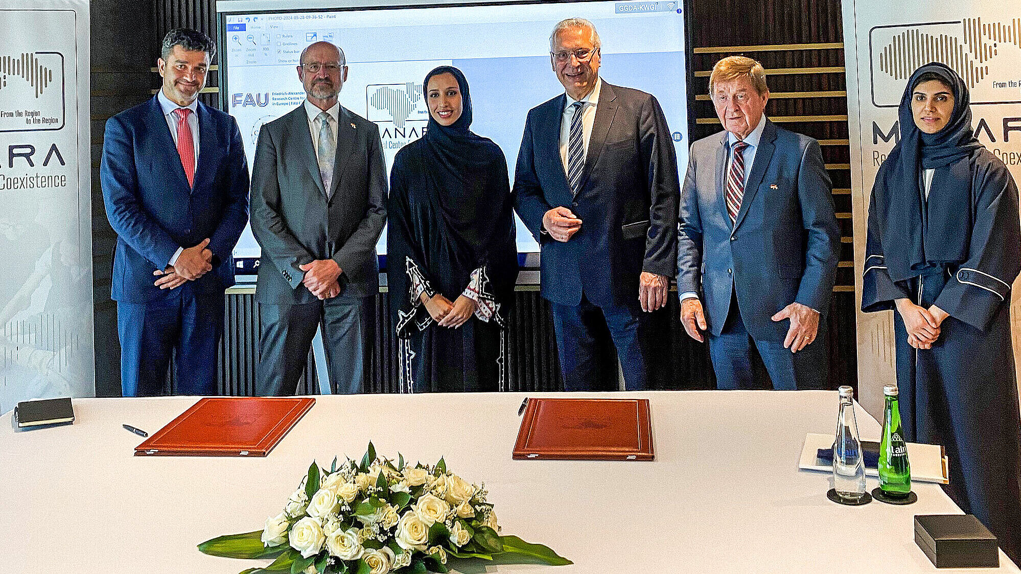Gruppenfoto vor Tisch mit Ledermappen und Blumen