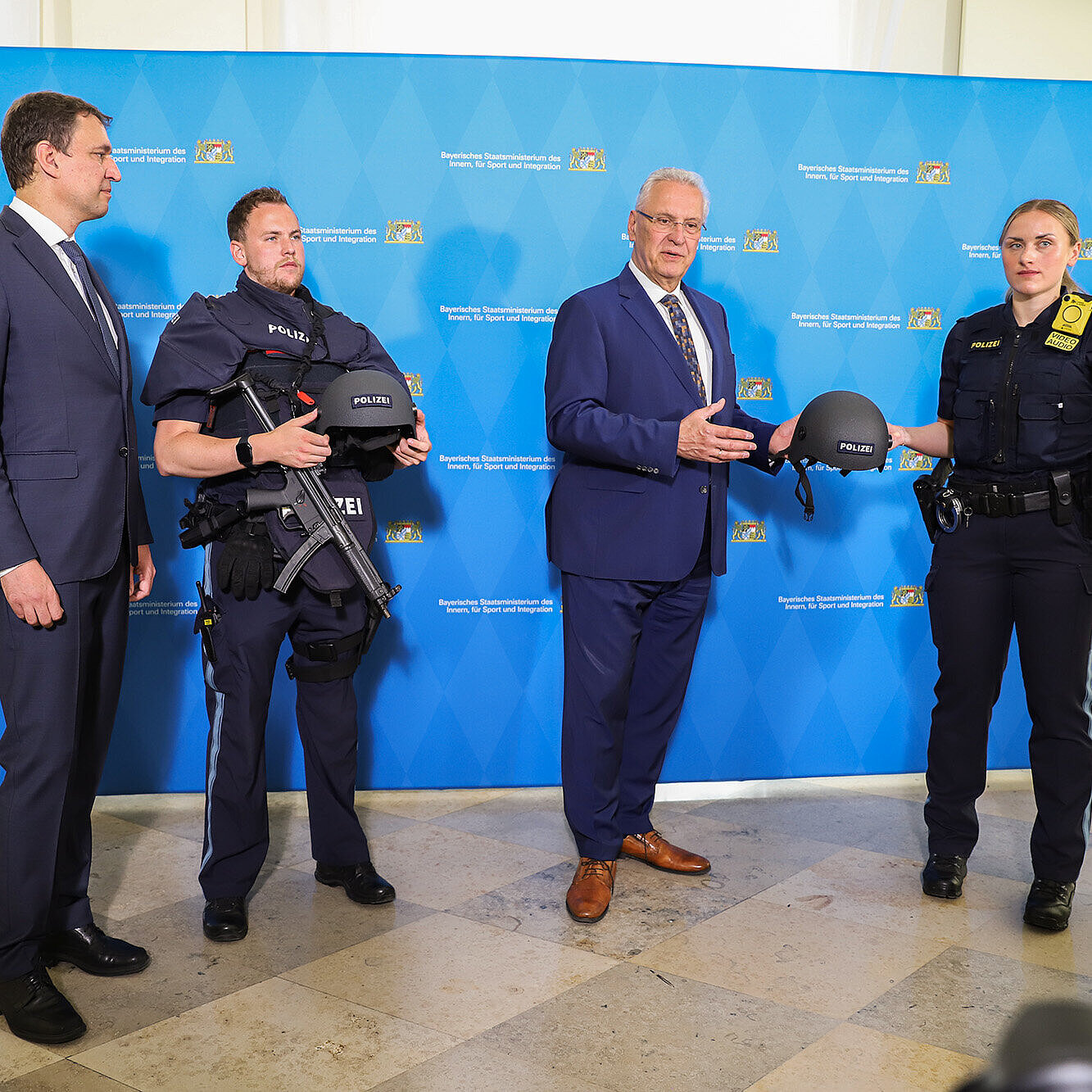 Herrmann und Eisenreich präsentieren mit zwei Polizeibeamten die Schutzausrüstung