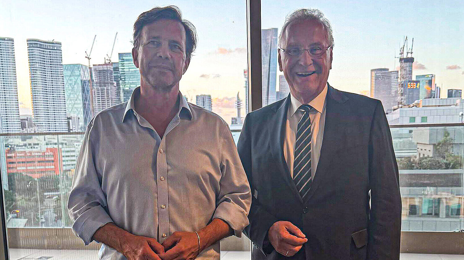 Auf dem Bild sind Botschafter Steffen Seibert und Innenminister Joachim Herrmann vor einer Skyline zu sehen.