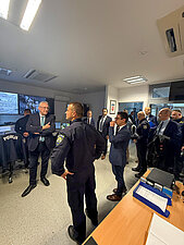 Eine Gruppe von Menschen in einem Raum, Innenminister Joachim Herrmann im Anzug, der im Mittelpunkt steht.