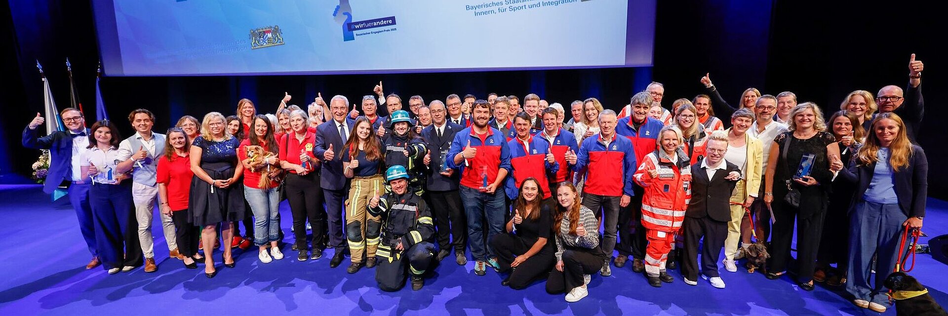 Auf dem Bild sind alle Preisträgerinnen und Preisträger sowie Laudatorinnen und Laudatoren des Bayerischen Engagiert-Preis 2025 gemeinsam mit Innenminister Joachim Herrmann auf der Bühne zu sehen.