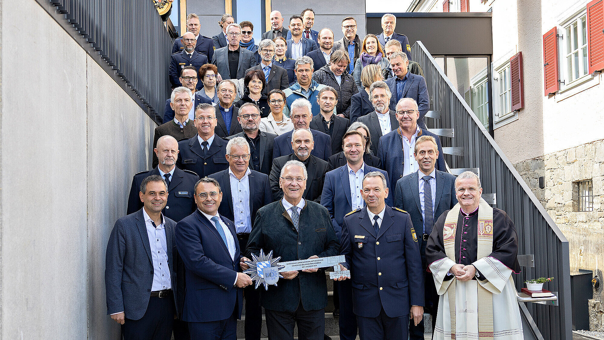 Gruppenfoto mit allen Beteiligten und großem Schlüssel mit Polizeistern auf einer Treppe