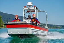 Drei BRK-Ehrenamtliche fahren in einem Rettungsboot über das Wasser