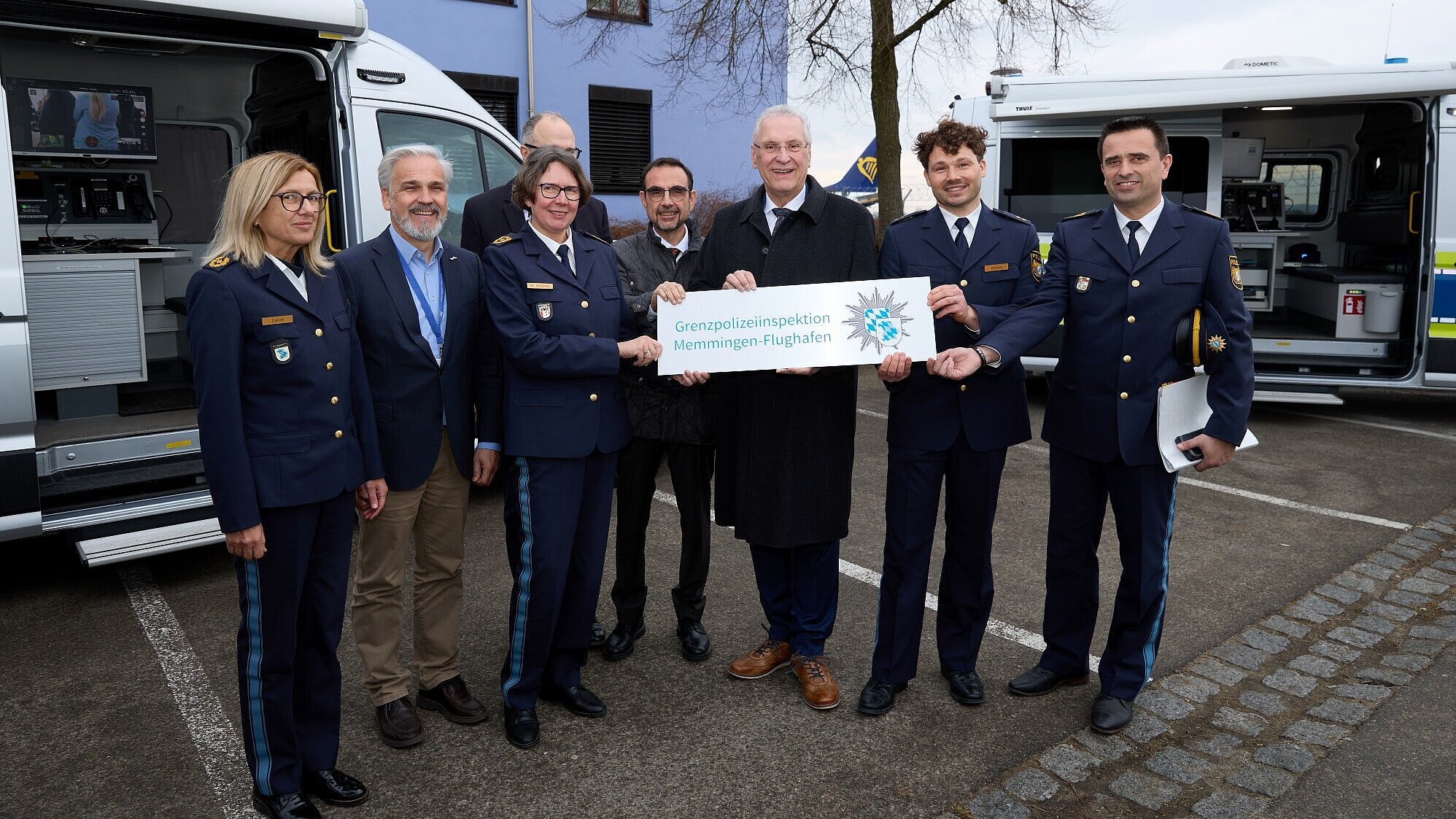 Innenminister Herrmann, Polizeipräsidentin Dr. Claudia Strößner und Weitere halten symbolisches Schild "Grenzpolizeiinspektion Memmingen-Flughafen"