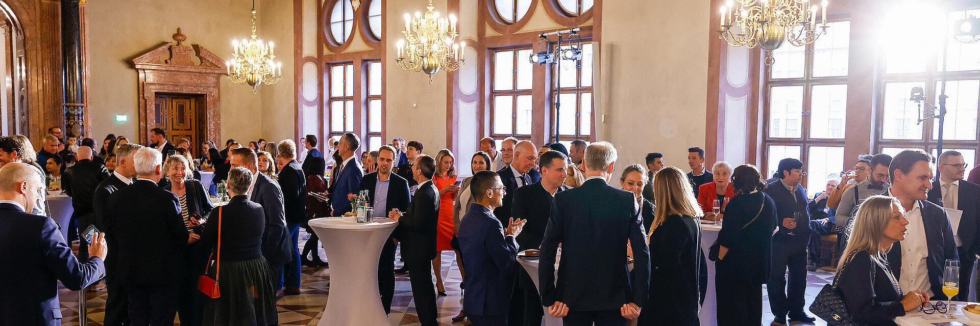 Gäste im Kaisersaal der Münchner Residenz an Stehtischen