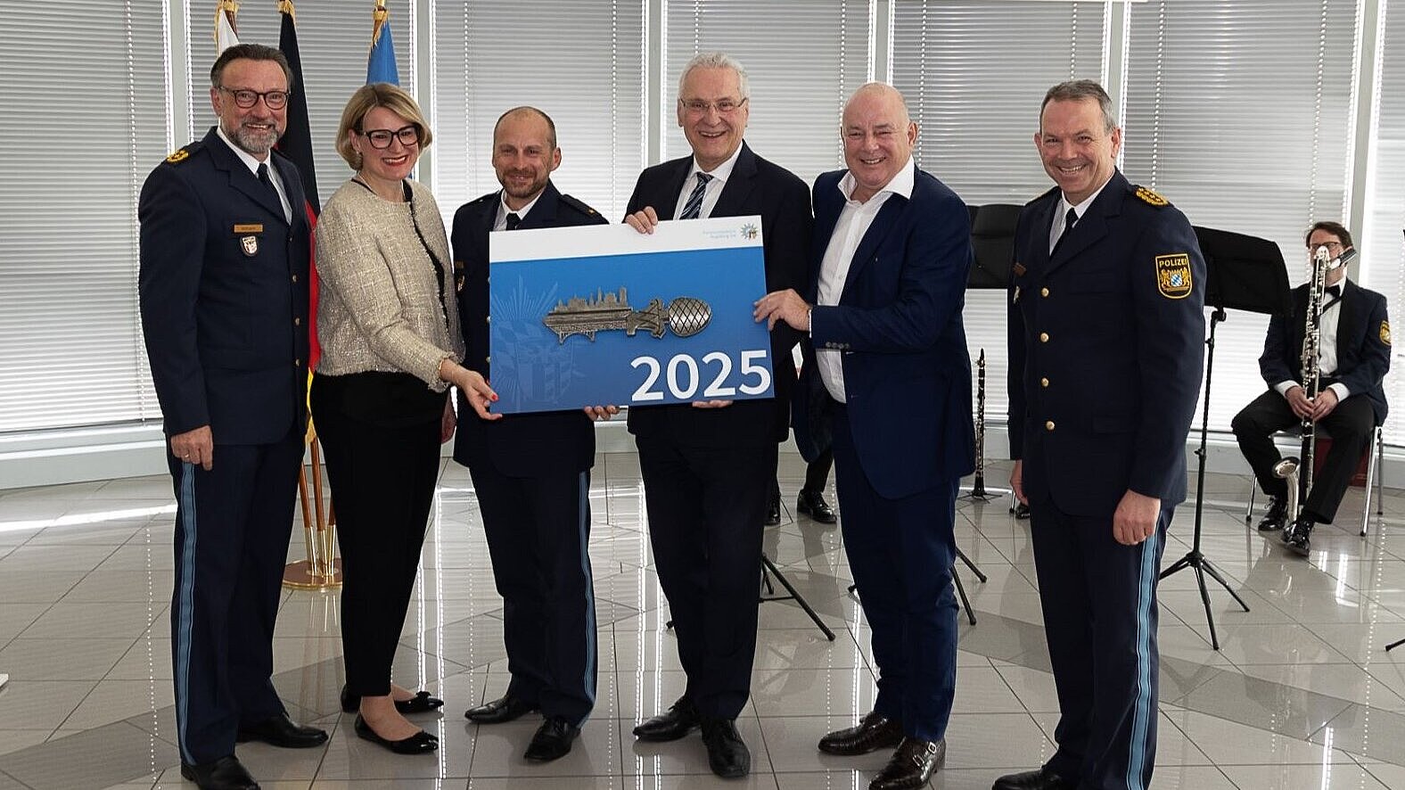 Auf dem Bild ist Innenminister Joachim Herrmann mit weiteren Ehrengästen bei der Einweihung der Räumlichkeiten der PI Augsburg Ost zu sehen. Herrmann hat einen symbolischen Schlüssel in der Hand.