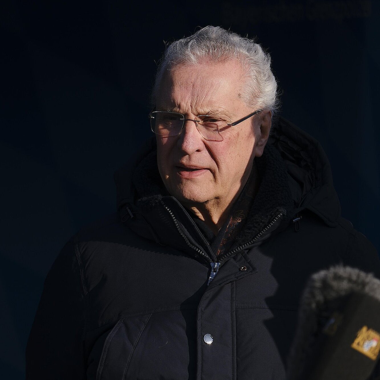 Herrmann im Dunklen vor Mikrofon, ernst blickend