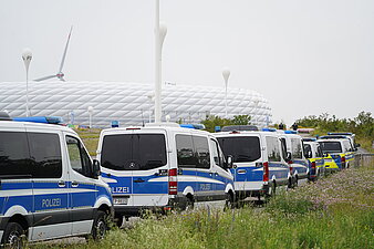 Polizeiautos und Polizeibusse hintereinander stehend vor der Allianzarena