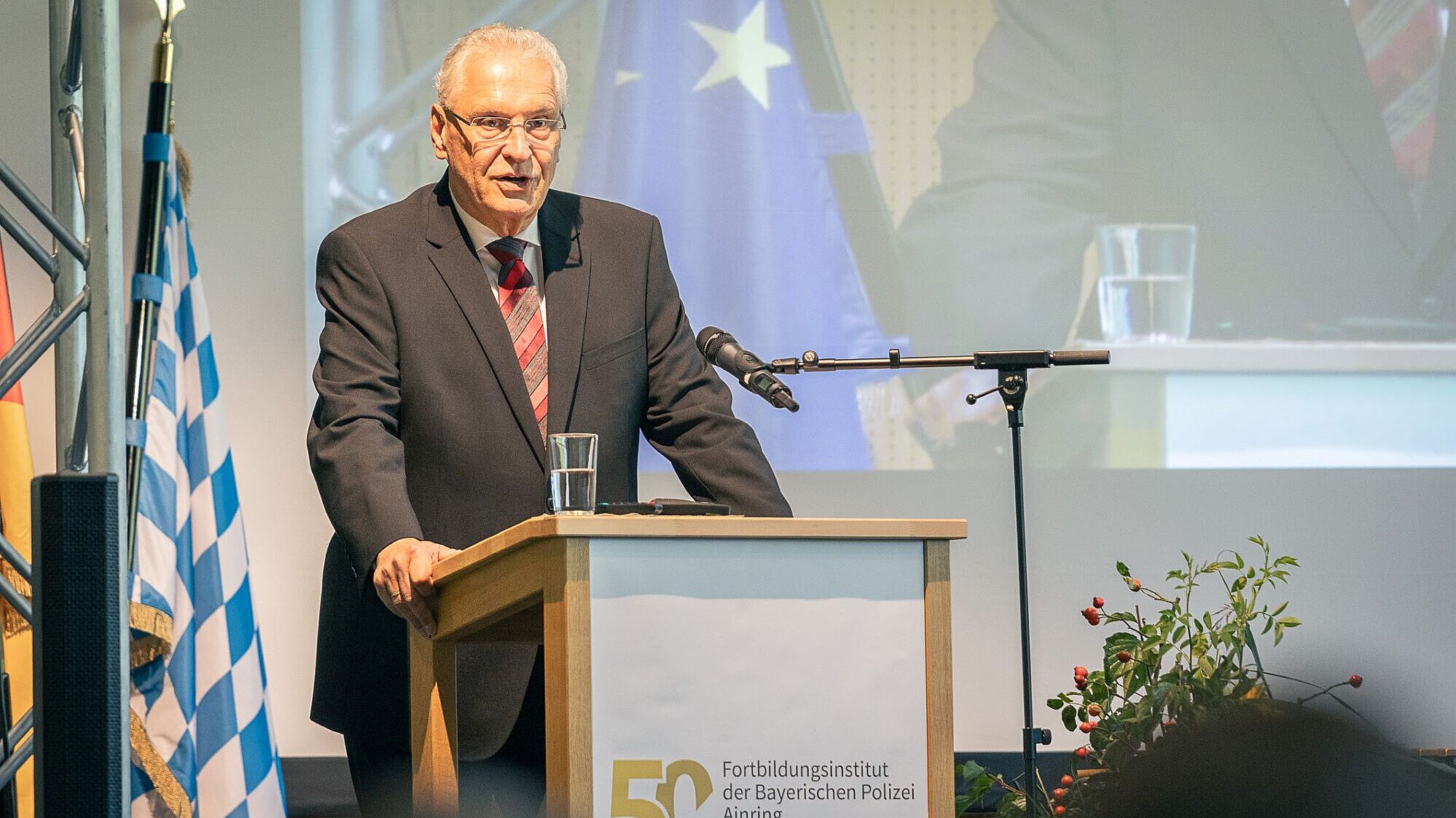 Innenminister Joachim Herrmann bei seiner Rede anlässlich von 50 Jahren Fortbildungsinstitut Ainring. Er steht am Rednerpult und schaut in die Menge