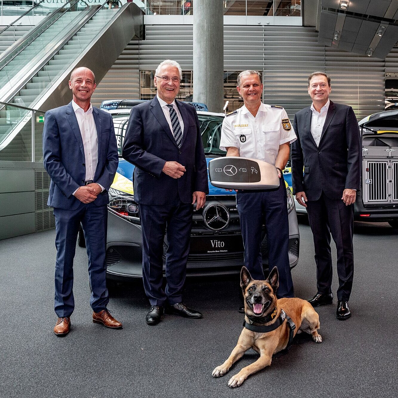 Auf dem Bild sind u.a. Innenminister Joachim Herrmann, ein Polizeihund und weitere offizielle Gäste zu sehen, vor einem neuen Einsatzfahrzeug der Münchner Polizei