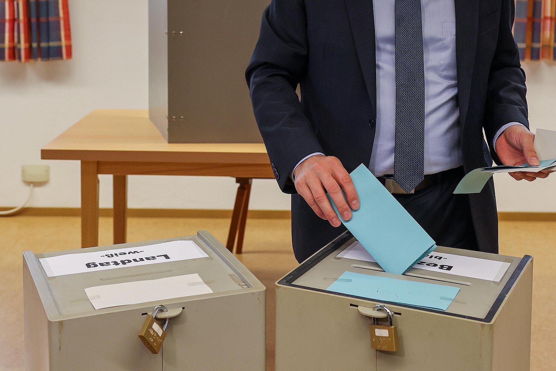 Eine Person die einen Wahlzettel in eine von zwei Wahlurnen einwirft