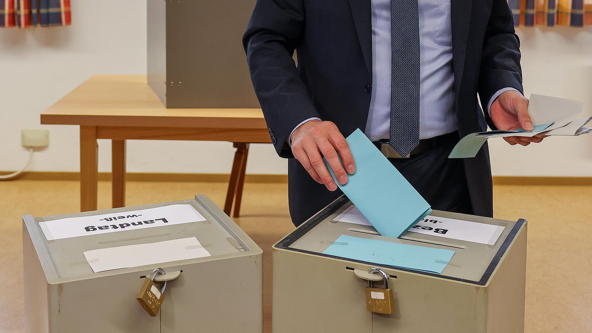 Eine Person die einen Wahlzettel in eine von zwei Wahlurnen einwirft