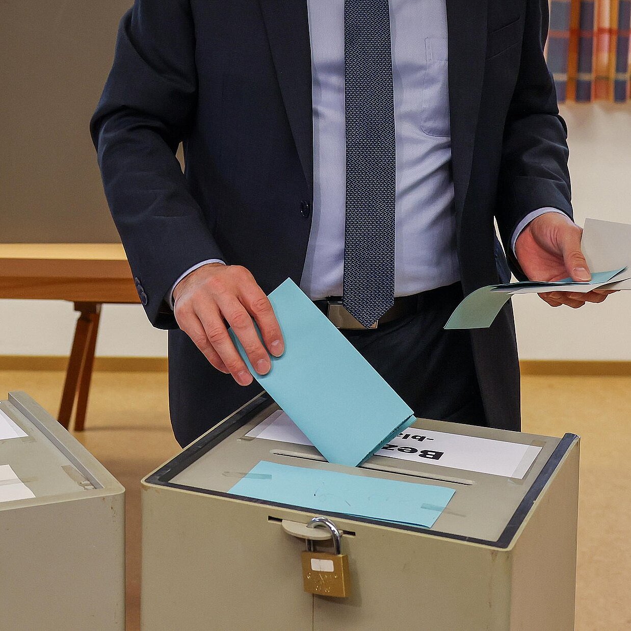 Eine Person die einen Wahlzettel in eine von zwei Wahlurnen einwirft