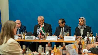 Mehrere Menschen sitzen um einen Tisch und interagieren miteinander.