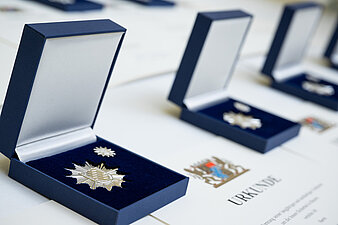 Mehrere Medaillen Stern der Sicherheit im geöffneten Etui mit Urkunde nebeneinander