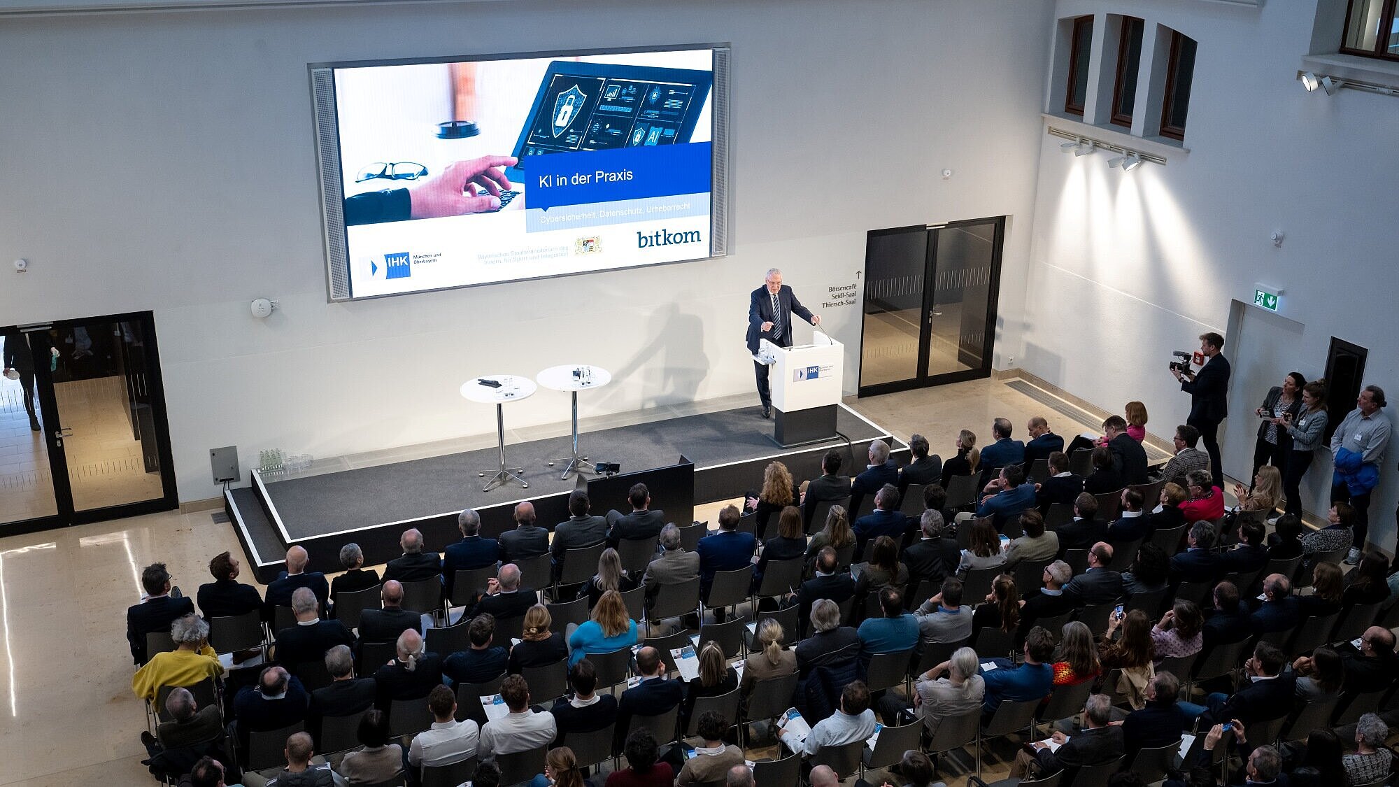 Blick von oben auf Publikum, Herrmann am Rednerpult bei Präsentation