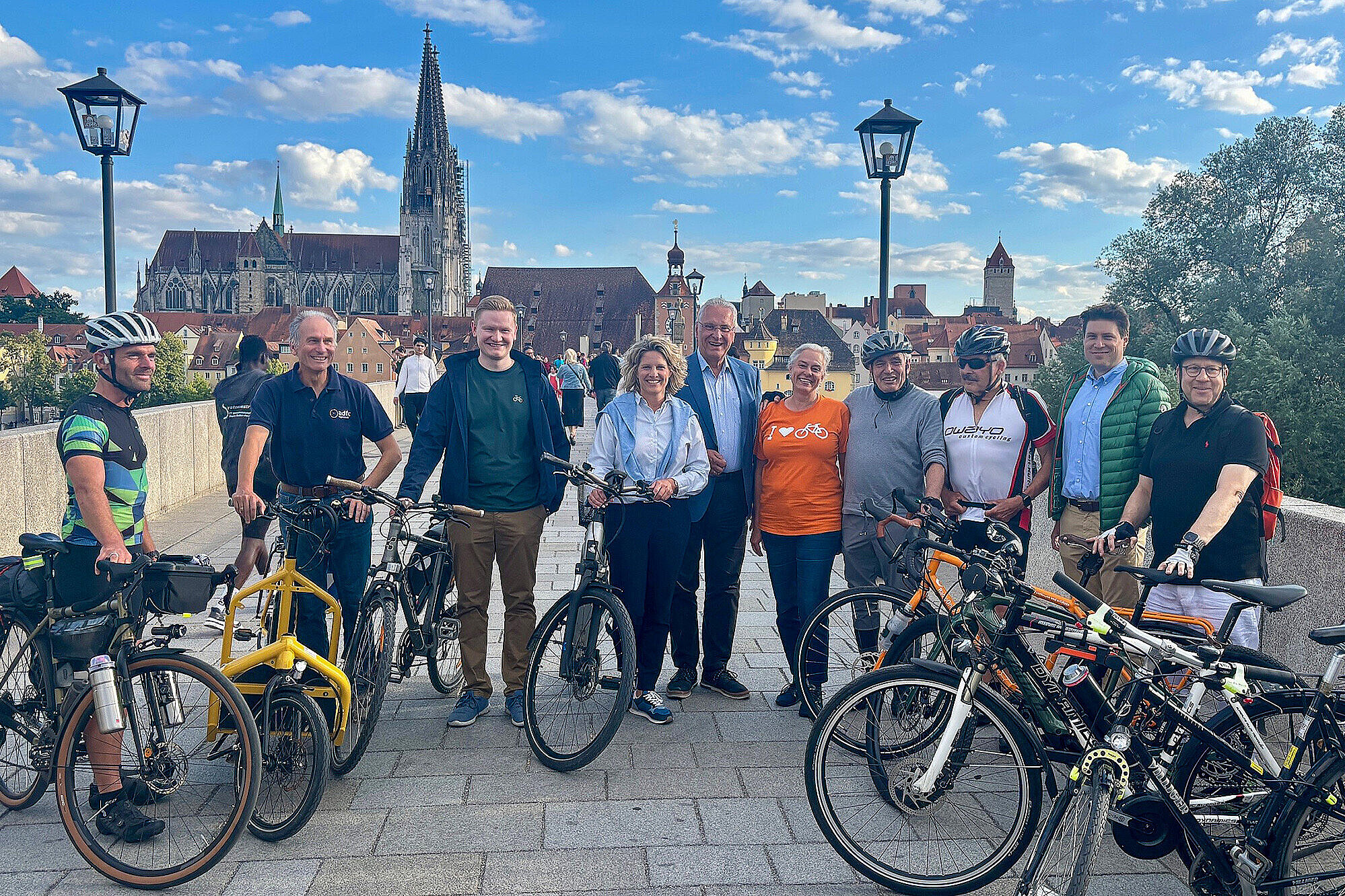 Eine Gruppe von Menschen mit ihren Fahrrädern stehen auf auf der Brücke in Regensburg Innenminister Herrmann steht in der Mitte , alle blicken in die Kamera.