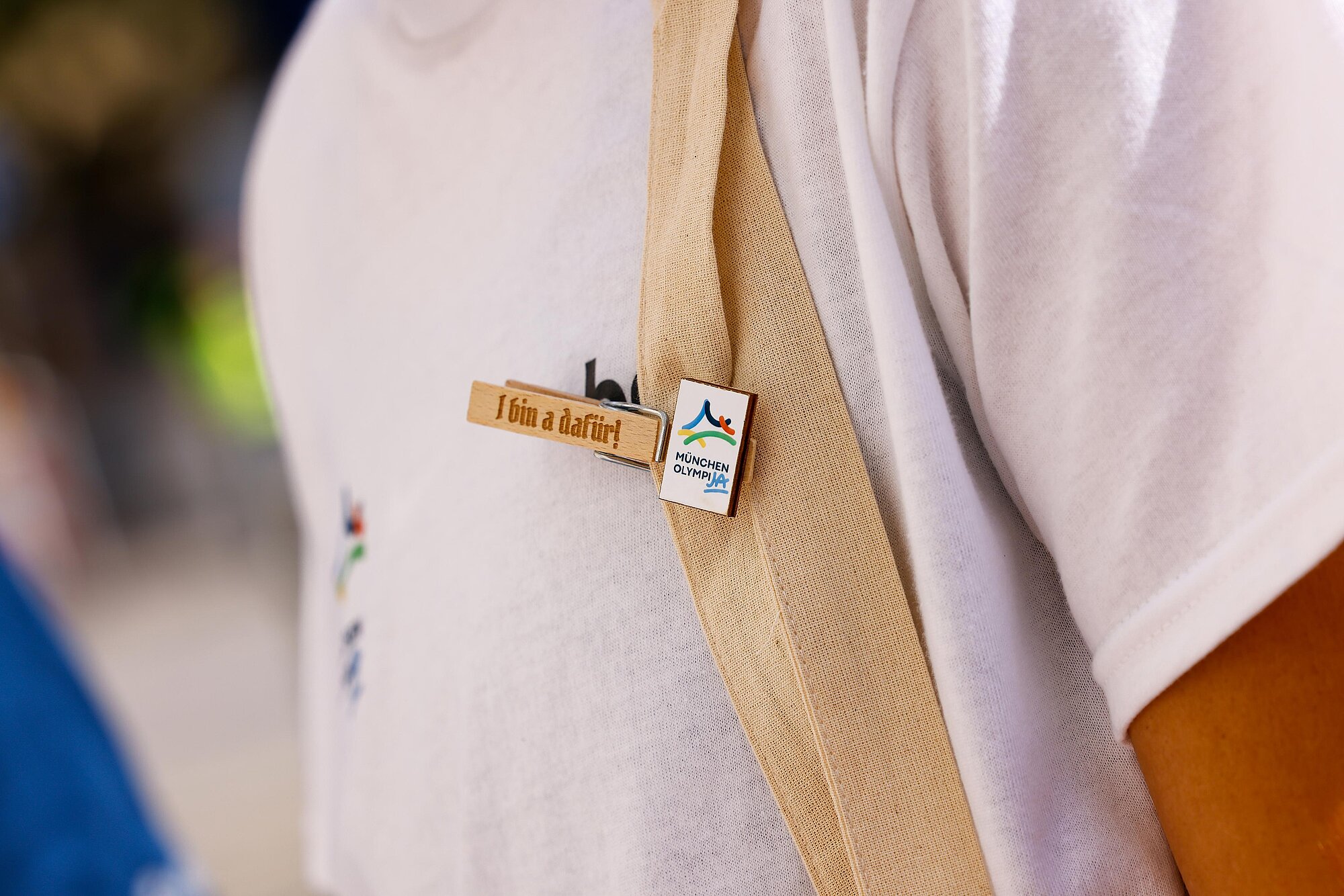 Detailaufnahme von einer Wäscheklammer an einer Person mit der Aufschrift "I bin a dafür" und dem OlympiJA-Logo