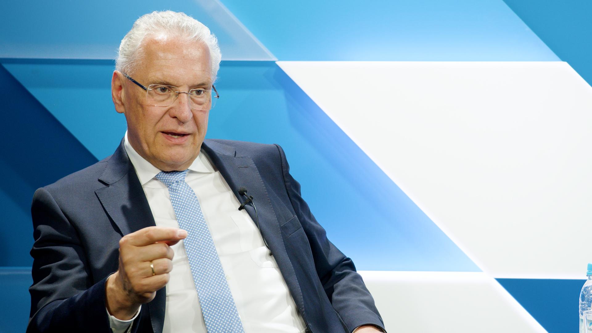 Innenminister Joachim Herrmann sitzend und gestikulierend, nachdenklicher Blick