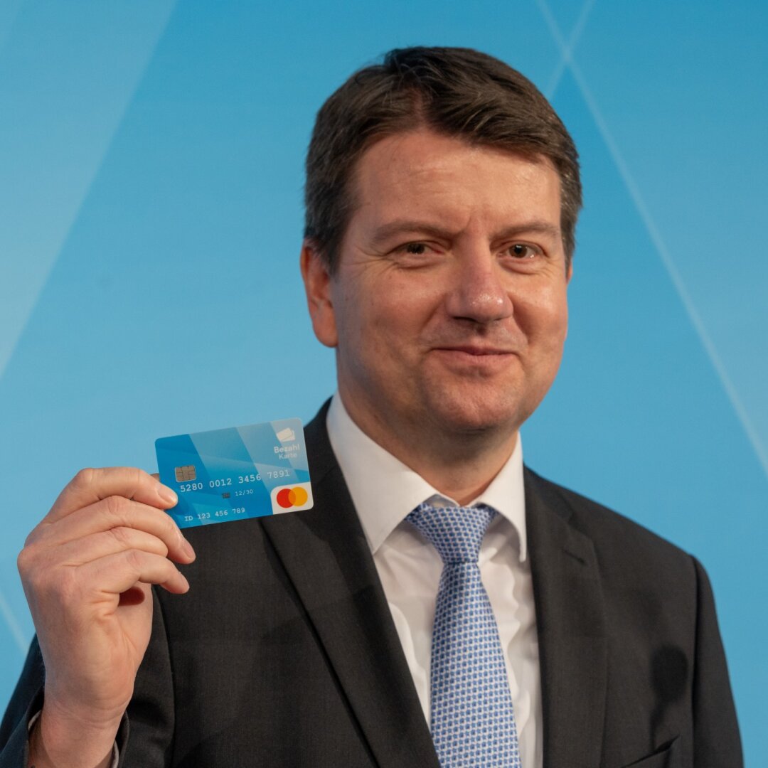 Auf dem Bild ist Innenstaatssekretär Sandro Kirchner zu sehen, der die Bezahlkarte in die Höhe hält.